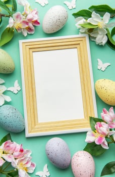 Easter eggs and flowers blank frame on a turquoise background photo
