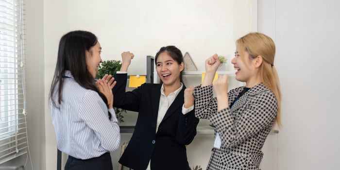 Excited businesswomen celebrating achievements with enthusiasm in a modern office environment. photo