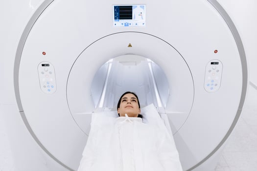 Female finished magnetic resonance imaging, Patient is moving out of MRI scanner capsule. Woman patient lies on an MRI scanner bed. Modern equipped cabinet in private clinic. Free copy space, ads photo