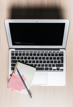 Laptop, notebook, and stationery arranged on wooden desk during productive work session photo