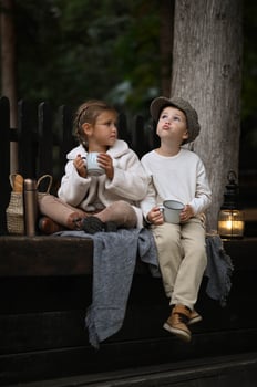In the fresh air, two children share a picnic, sipping tea from a thermos and tasting delicious treats. photo