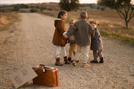 The children dance playfully on the road, their vintage clothes flowing as they wait beside their suitcase and North Pole sign photo