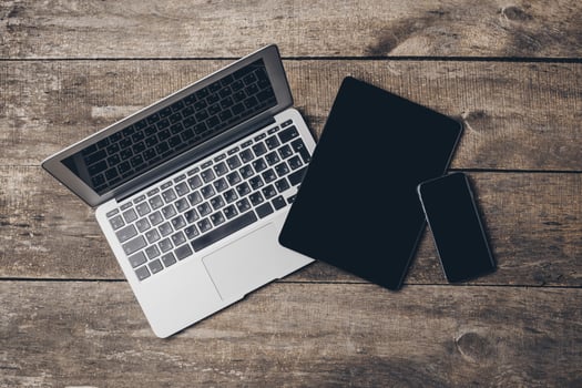 Multiple digital devices arranged on a wooden surface with a natural aesthetic during daylight hours photo
