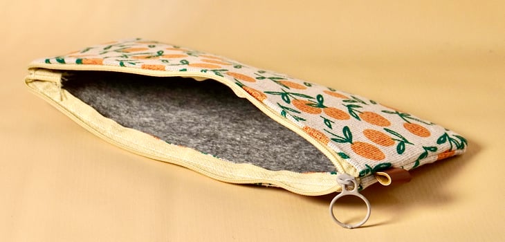 Empty opened pencil case with orange fruit fabric design isolated on horizontal brown cream background. photo