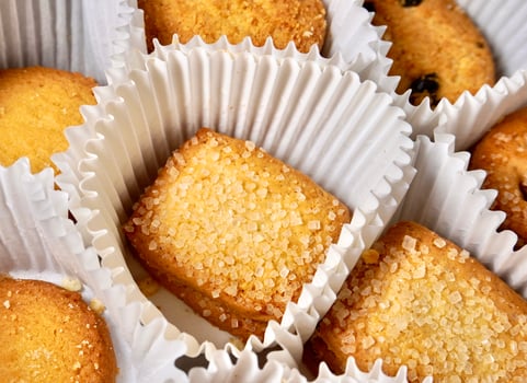 Close up yummy sugar coated butter cookies with white paper cups isolated on full frame horizontal background. photo