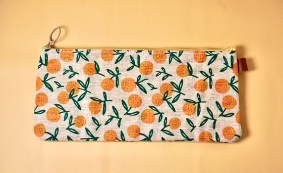 Pencil case with orange fruit fabric design isolated on horizontal brown cream background from top angle view. photo