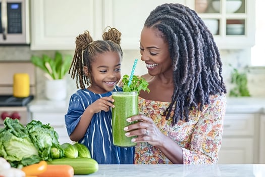 Mother and daughter smiling and holding green smoothie in kitchen photo
