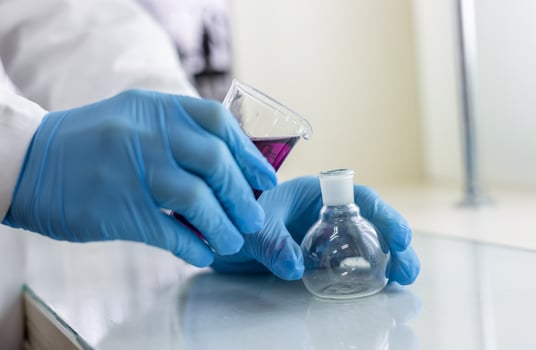 A person in a lab coat is holding a test tube photo
