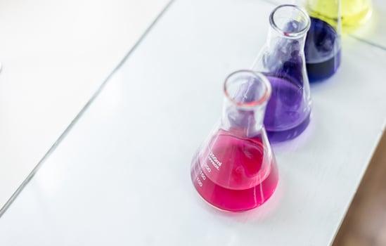 Three colorful liquid flasks sit on a table photo