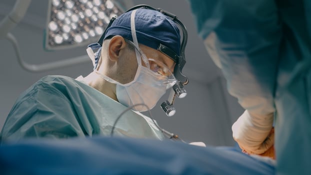 Close up surgeon man in protective mask physician doctor medic team operate patient laparoscopy surgical operation microscope surgery with medical tools in operating room hospital clinic health care photo