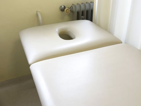 Empty white massage table in spa treatment room with soft lighting photo