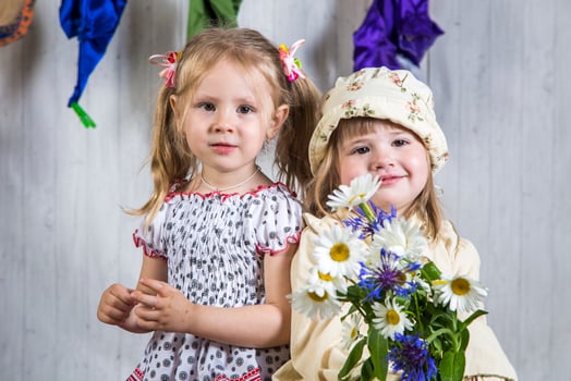 Two little girls holding flowers and posing for the camera photo