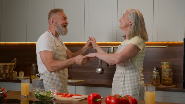 Romantic senior retired Caucasian family couple dancing waltz celebrate marriage anniversary cooking dinner old husband spin mid-aged wife in dance listen music at kitchen happy woman and man have fun photo