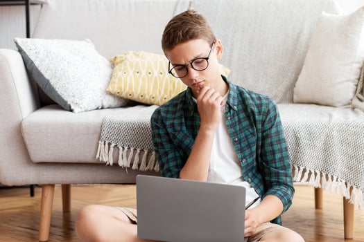 Smart schooler doing homework, using laptop, reading books, home interior, copy space photo