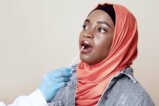 Coronavirus, COVID-19 pcr test concept. Nurse taking oral swab for coronavirus sample test from potentially infected muslim african american woman, beige studio background, closeup photo
