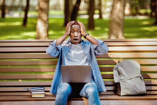 Big failure. Young black guy holding his head in panic near laptop computer at city park photo