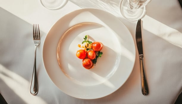 luxurious dining table setting featuring plate with vibrant tomatoes and fresh herbs, illuminated by soft sunlight photo