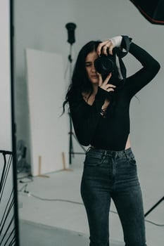 A young female photographer with a camera in her hands poses in the studio. photo