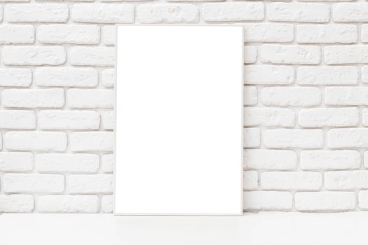 Blank canvas displayed against a white brick wall at an artist's studio during daylight hours photo