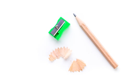Colorful pencil sharpener next to wooden pencil and shavings on a clean white background photo