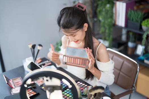 a woman is sitting at a desk with makeup products. photo