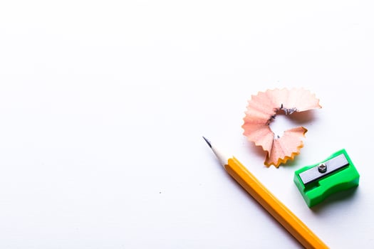 Pencil, sharpener, and shavings on white background create a simple workspace scene photo