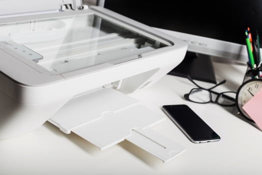 Office lighting highlights a modern printer beside a smartphone and a desk clock in a productive workspace photo