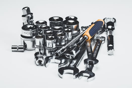 Collection of various hand tools including sockets, wrenches, and a ratchet set on a white surface for automotive repairs photo