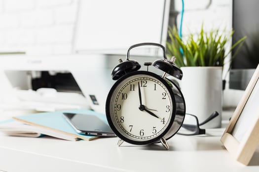 Classic black alarm clock on a modern workspace with plants and technology in a bright office environment photo