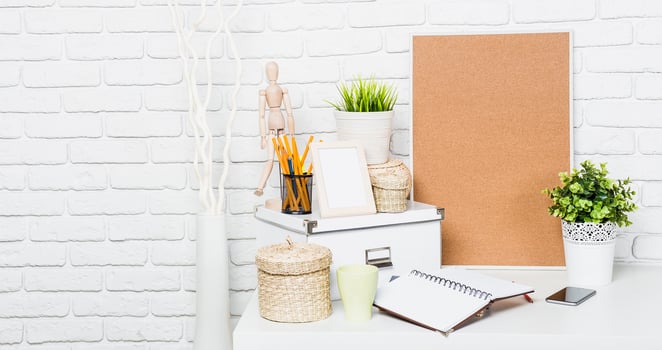 Workspace setup featuring organization tools, plants, and creative supplies in a bright room with white brick walls photo