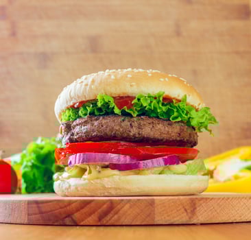 Juicy burger stacked with fresh toppings on a wooden surface in a cozy kitchen setting photo