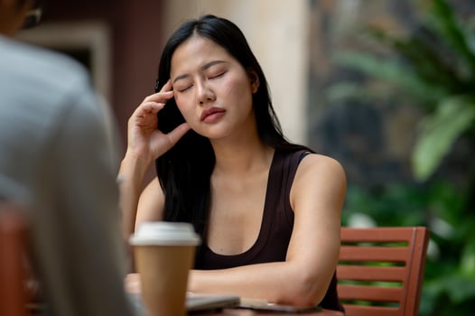 A tired, stressed Asian woman has a headache during an informal meeting with her colleague. photo
