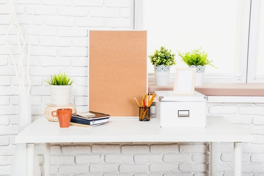 Stylish workspace design featuring plants, stationery, and a corkboard on a clean desk near a window photo