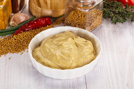 A bowl of mustard next to a bowl of spices photo