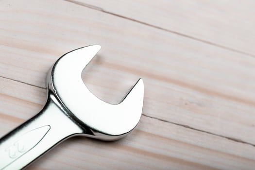 Close-up view of a shiny wrench resting on a wooden surface in a workshop setting during daylight hours photo
