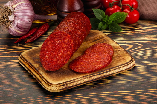A cutting board with a piece of salami on it photo