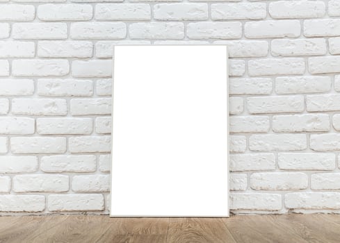 Blank white canvas positioned against a textured white brick wall in a simple interior setting photo