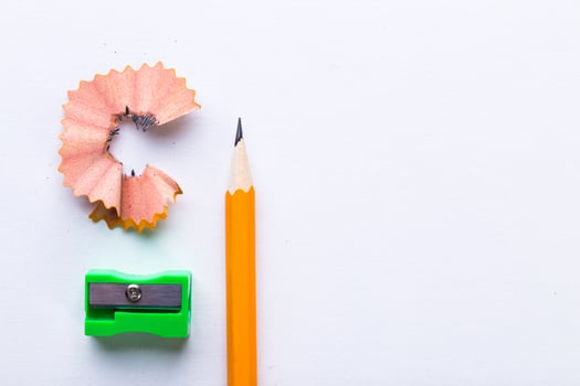 Bright orange pencil with sharpener and shavings on a clean surface photo