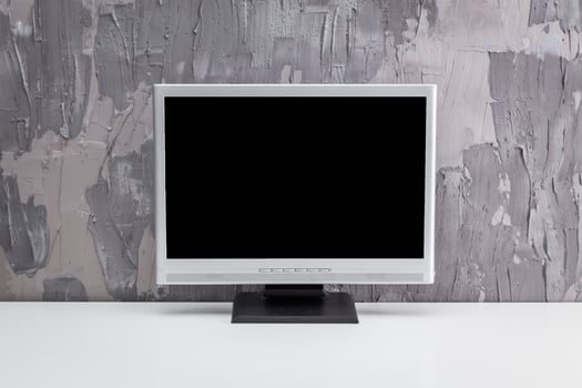 Empty desktop monitor standing on a minimalistic white table against a textured gray wall photo