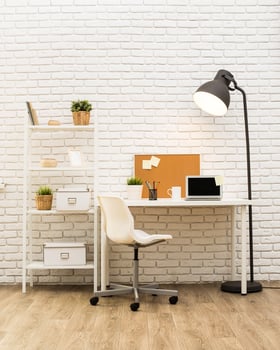 Modern workspace featuring a clean desk, shelving, and warm lighting in a minimalist setting photo