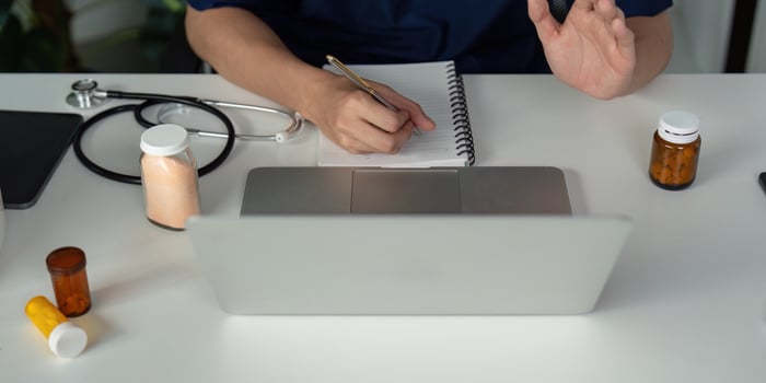 Medical student studying and taking notes while examining medication bottles at a desk with a laptop. photo