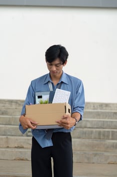 Young professional reflecting on career change while carrying a box of personal items from the office. photo