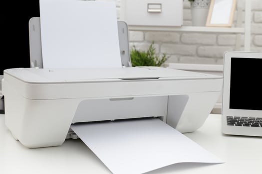 Modern printer printing documents on a white table in a cozy workspace with a laptop and decor photo