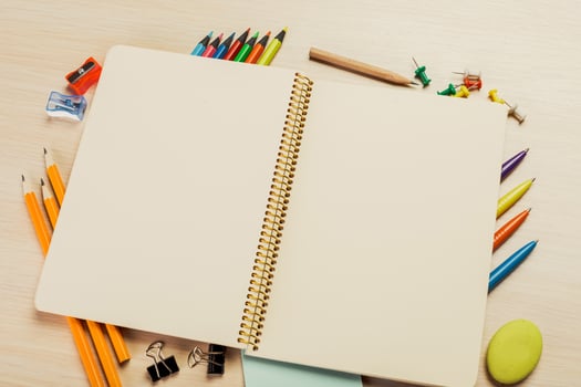 Blank notebook surrounded by colorful stationery on a desk ready for creativity at home or school photo