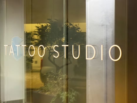 Tattoo studio sign on glass door with interior reflection photo
