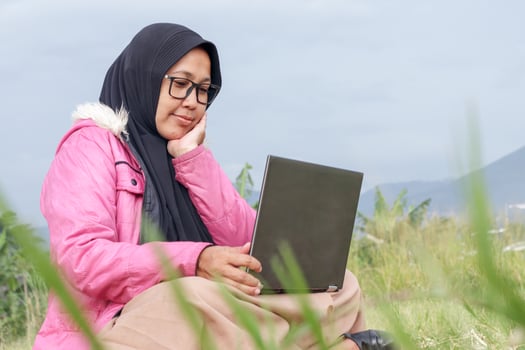 Muslim Woman Working on Laptop in Nature with Scenic Background photo