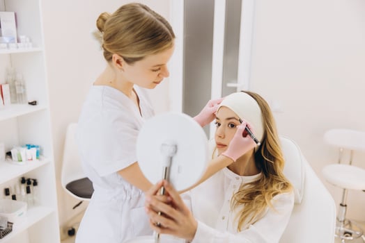 Beautician marking woman's eyebrows before permanent make up procedure in aesthetic medicine clinic photo
