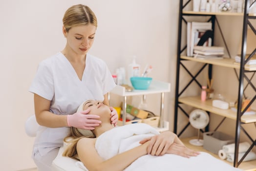 Pink gloved beautician performing facial massage on reclining woman during spa treatment photo