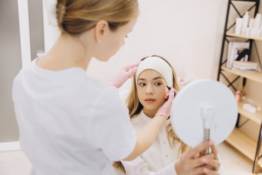 Cosmetologist marking face before botulinum toxin injections for wrinkles smoothing in beauty salon photo
