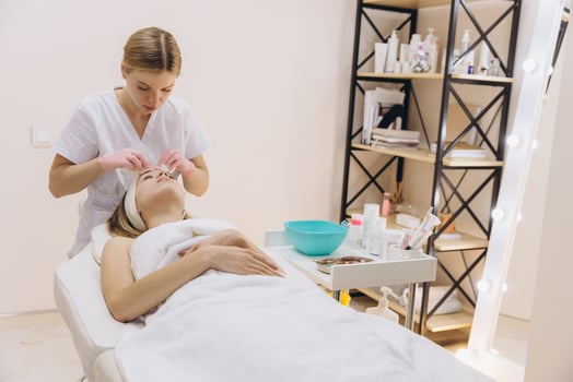 Cosmetologist cleaning the facial skin of a young woman reclining on a massage table in a serene beauty salon environment photo